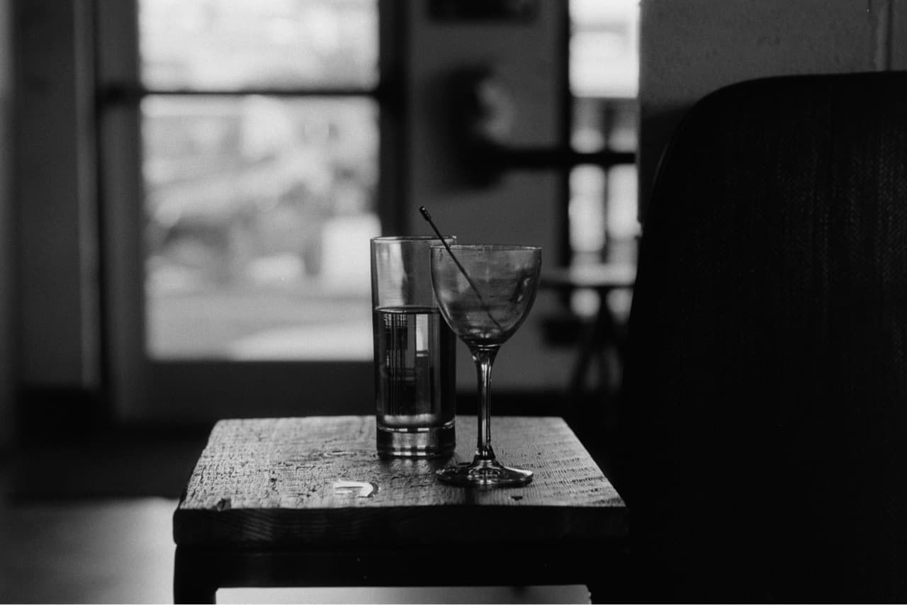 Two cocktail glasses in a dimly lit bar, backlit