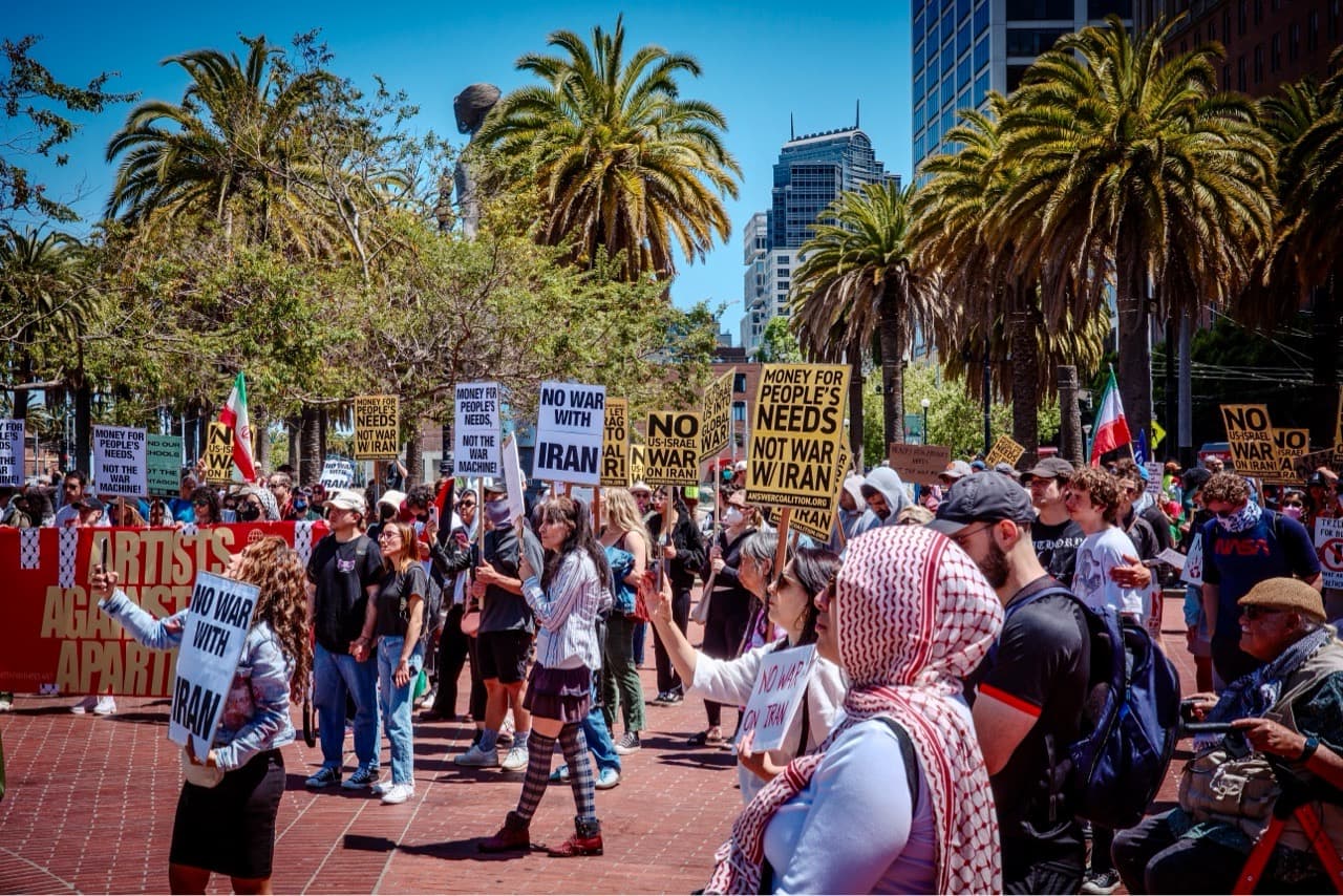 Crowd at a mass protest, blue sky and palm trees in the background
